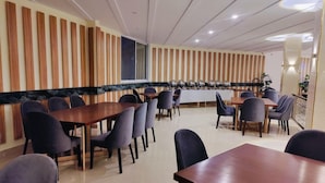 A modern dining area with multiple tables and chairs, a wooden accent wall, and a marble countertop. - Pinemont Hotel Murree (Murree)