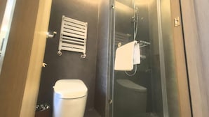 Un baño pequeño con inodoro, cabina de ducha y barra para toallas.
