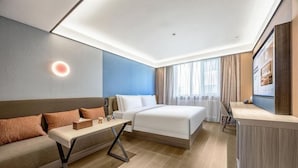 Una habitación de hotel con una cama, un sofá, un escritorio y un televisor.