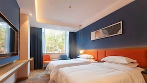 Habitación de hotel con dos camas, un escritorio, una silla y un ventanal grande.