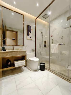 A modern bathroom with a large mirror, a toilet, a shower enclosure, and a vanity with a sink and towel rack. - Lesden Hotel (Guangzhou)