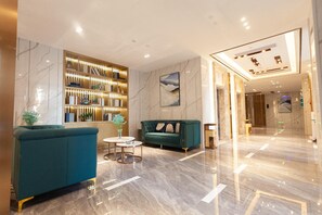 A modern lobby with a teal sofa, a round coffee table, and a marble floor. - Lesden Hotel (Guangzhou)
