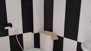 Un baño con inodoro, lavabo y pared revestida de baldosas blanco y negro.