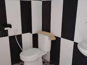 Un baño con inodoro, lavabo y pared revestida de baldosas blanco y negro.
