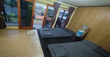 A room with two beds, a water dispenser, and a view of the outside.
