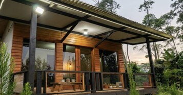 Una cabaña de madera con balcón, ventanas amplias y ventilador de techo.