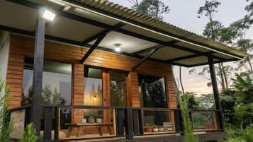 Una cabaña de madera con balcón, ventanas amplias y una lámpara en el techo.