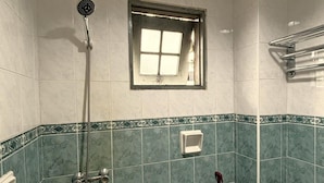 Ein Badezimmer mit Dusche, Fenster und Toilette.