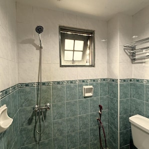 Une salle de bain avec une douche, une fenêtre et des toilettes.
