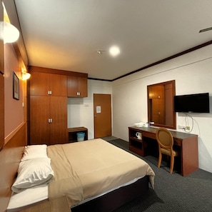 Une chambre d’hôtel équipée d’un lit, d’un bureau, d’une chaise, d’une télévision et d’armoires en bois.