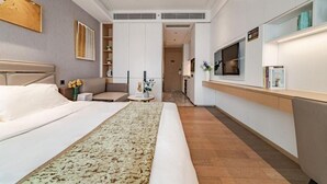 Une chambre d’hôtel moderne équipée d’un grand lit, d’un canapé, d’une petite table et d’un coin cuisine.