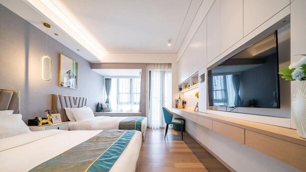 Une chambre d’hôtel avec deux lits, une télévision, un bureau et une grande fenêtre.