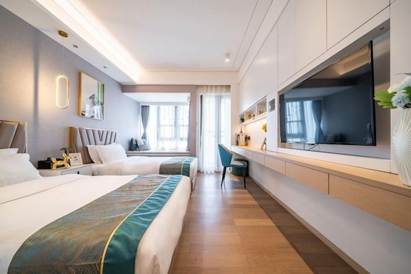 Habitación de hotel con dos camas, televisión, escritorio y ventana grande.