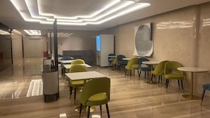 Un comedor moderno con mesas y sillas, suelo de mármol y un diseño de techo contemporáneo.