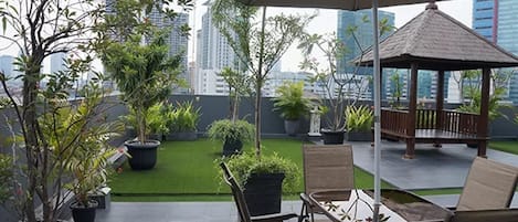 A rooftop patio with outdoor seating, potted plants, and a view of the city skyline.