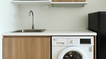 A compact kitchen with a microwave, sink, and washing machine.