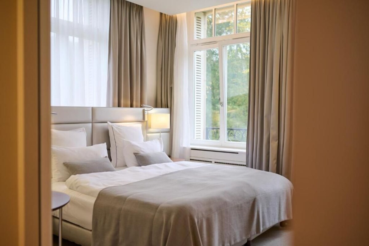 Een hotelkamer met een bed, nachtkastjes en een raam met gordijnen.
