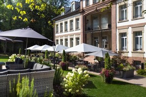 Een terras met parasols en rieten meubels.