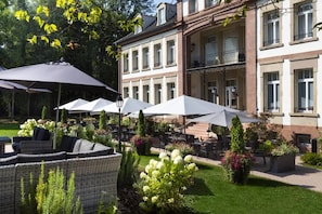 An outdoor seating area with umbrellas and wicker furniture. - Chateau Hochberg Hotel et Restaurant (Wingen-sur-Moder)