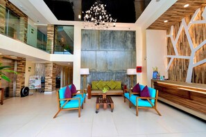 A modern lobby with a reception desk, seating area with sofas and armchairs, a chandelier, and a large wall with a geometric pattern. - Ferra Premier Boracay by JG (Boracay Island)