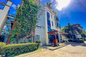 Un edificio moderno con ingresso coperto, un logo ben visibile e un'area giardino curata.