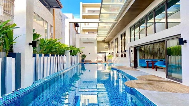 Un hotel moderno con piscina central, barandillas de vidrio y un diseño limpio y contemporáneo.