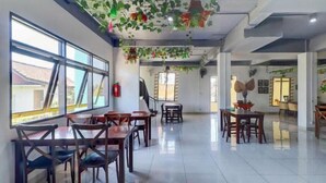 A spacious dining area with multiple tables and chairs, large windows, and a staircase leading to another level. - Collection O Near Monkey Forest Formerly Hepiyuk Guest House (Ubud)