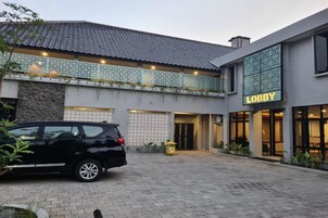 Un edificio con un cartel que dice 'Lobby', un coche estacionado al frente y una pared de piedra.