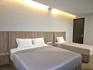 Una habitación de hotel con dos camas, cabecera de madera y una puerta.
