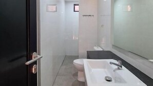 A modern bathroom with a large mirror, a white sink, and a toilet. - Hotel Anda (Jember)