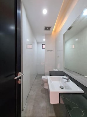 Un baño moderno con un espejo grande, un lavabo blanco y un inodoro.