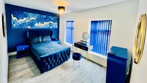 A modern bedroom with a large bed, a desk, a chair, and a large painting on the wall. - 4-bed House, Sleeps 9 w Garden & On-street Parking (Liverpool)