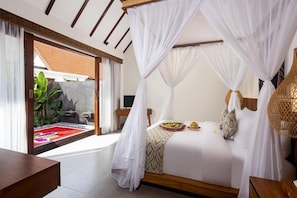 A bedroom with a canopy bed, a view of a garden, and a wooden bench. - Jenna Villa by Genuinehost (Ubud)