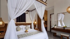 A bedroom with a four-poster bed, a bedside table, a nightstand, a mirror, and a bench. - Jenna Villa by Genuinehost (Ubud)