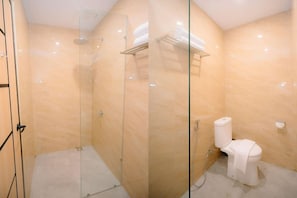 Un baño con ducha envuelta en vidrio, inodoro y perchero para toallas.