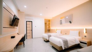 Une chambre d’hôtel avec deux lits, un bureau et une télévision.