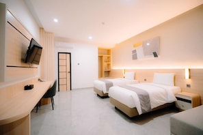 Una habitación de hotel con dos camas, un escritorio y una televisión.