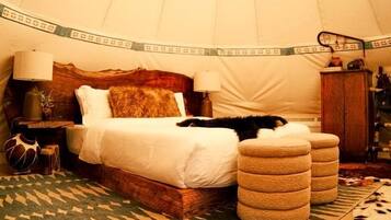 A room with a bed, a rug, and a wooden ceiling structure.