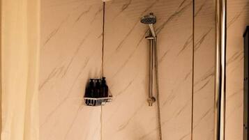 Une salle de bain avec une douche, un porte-serviettes et un rideau.