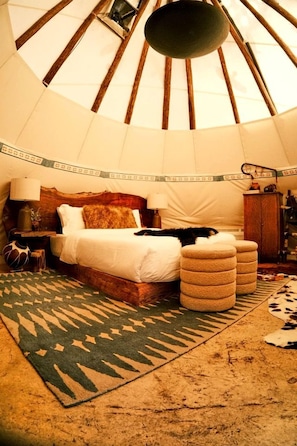 Una habitación con cama, alfombra y estructura de techo de madera.