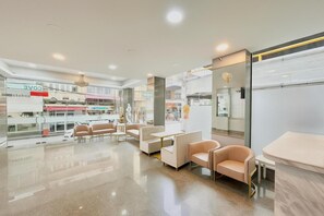 A modern interior with seating areas, a glass wall, and a view of the street. - Abcyq Hotel Bangkok (Bangkok)