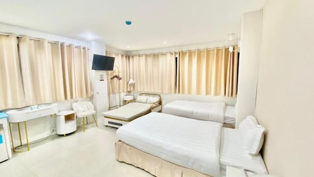 Quarto de hotel com cama, escrivaninha, cadeira e televisão.