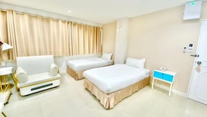 Quarto de hotel com duas camas, uma mesa de cabeceira, uma cadeira e uma pequena escrivaninha com abajur.