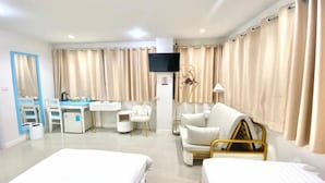 Quarto de hotel com duas camas, uma escrivaninha, uma cadeira, uma televisão e cortinas.