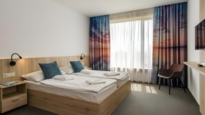 A hotel room with a double bed, bedside tables, a desk, a chair, and a TV. - Sports Academy Hotel (Balatonfured)