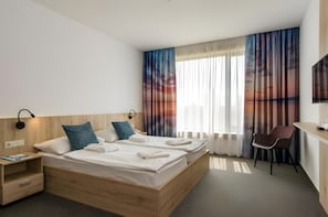 Una camera d'albergo con un letto matrimoniale, comodini, una scrivania, una sedia e un televisore.