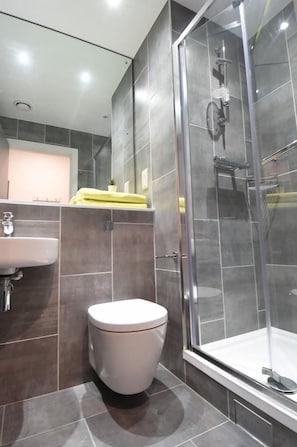 A modern bathroom with a toilet, sink, and glass-enclosed shower. - Yugo Lee Point (Cork)