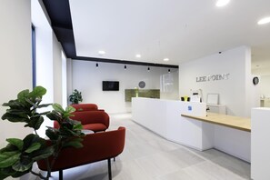 Un área de recepción moderna con escritorio, sillas y un reloj.