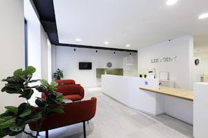Un área de recepción moderna con escritorio, sillas y un reloj.