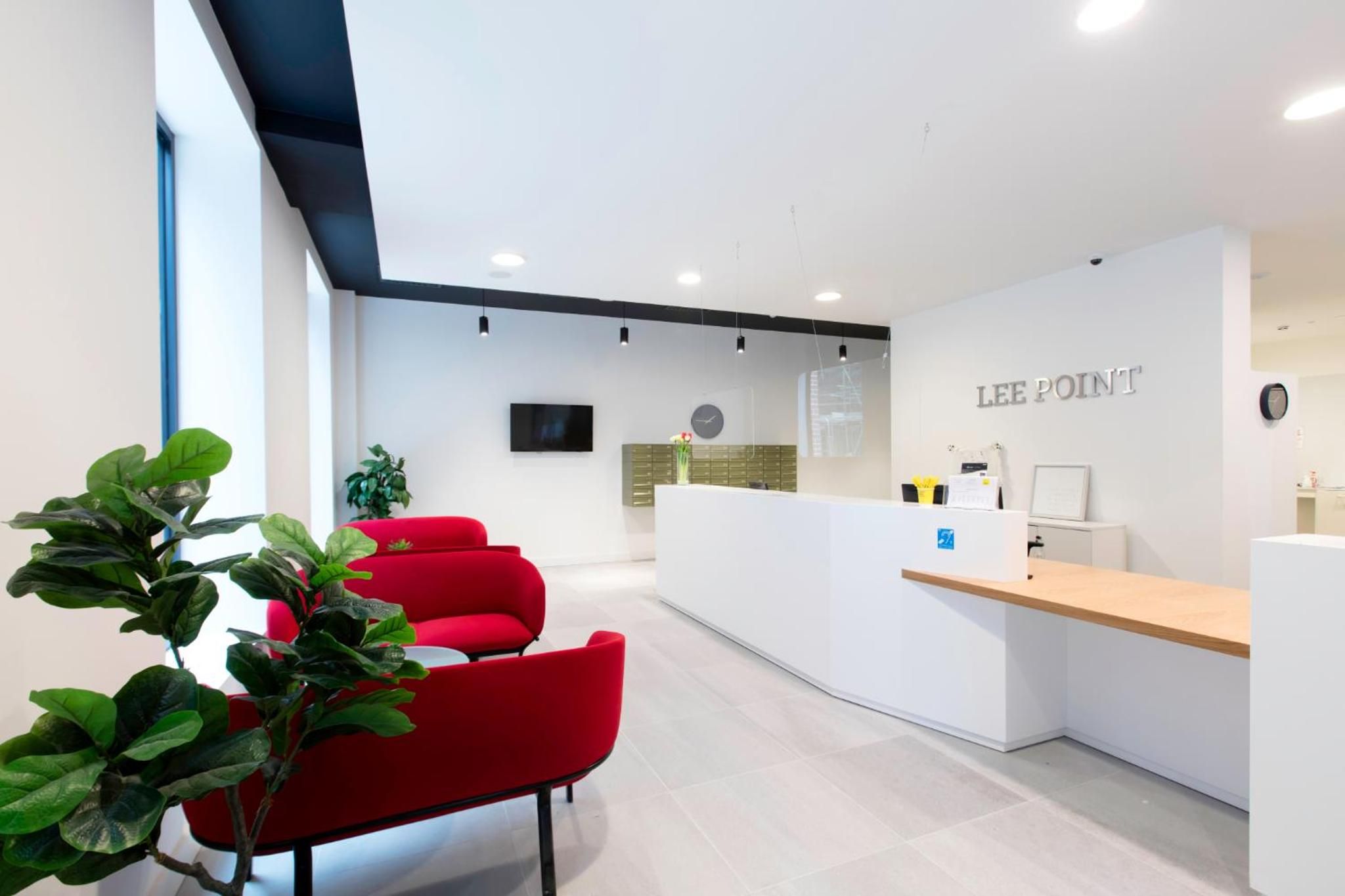 A modern reception area with a counter, seating, and a wall-mounted clock.